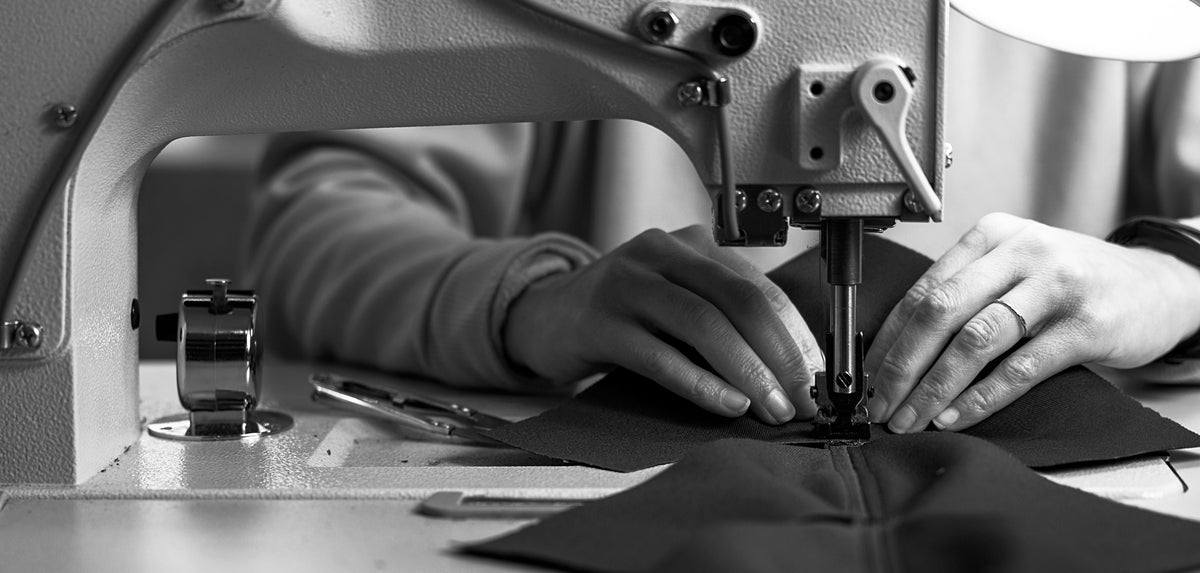 Hands guiding hat fabric through an industrial sewing machine at Sandlot Goods.